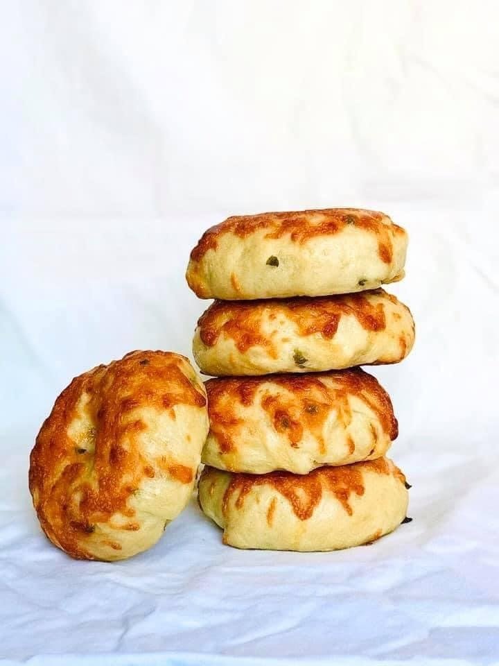 A stack of jalapeéo cheddar sourdough bagels with melted cheese and green pepper flecks