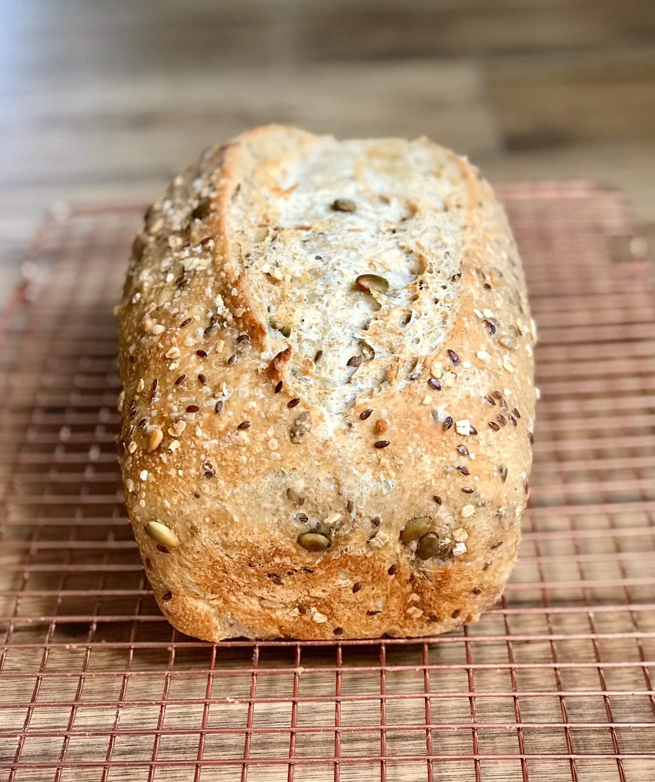 A seeded multigrain sourdough loaf topped with oats, flax and pumpkin seeds